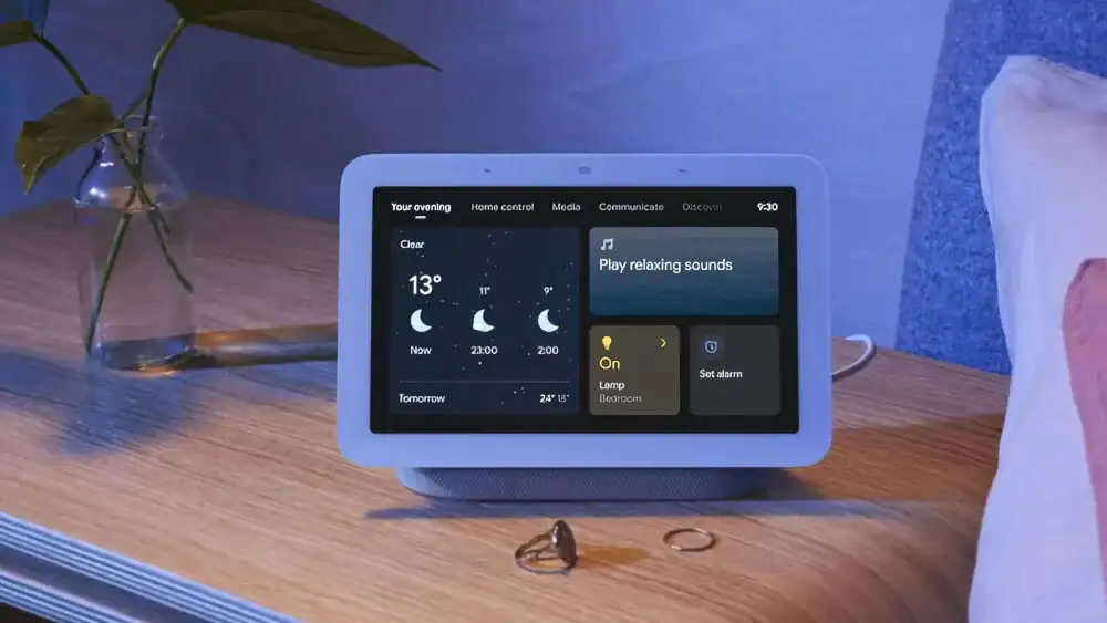 Google Nest Hub 2 na stoliku nocnym z nocnym trybem: pogoda, kontrola światła, dźwięki relaksacyjne i alarm.