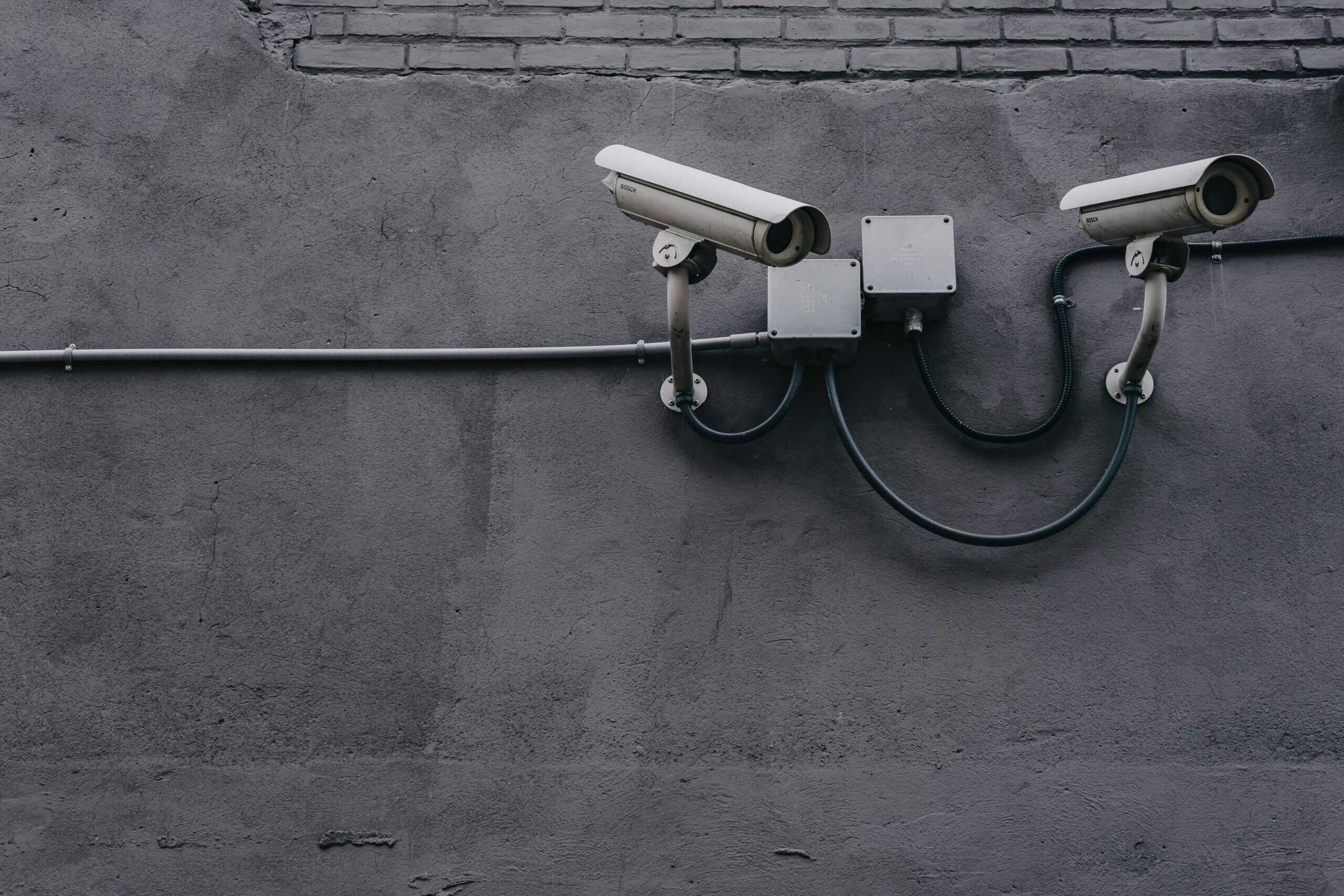 Dwie kamery monitoringu przemysłowego zamontowane na szarej betonowej ścianie – element systemu bezpieczeństwa Smart Home