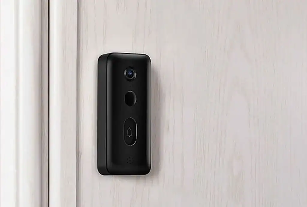 Czarny wideodomofon Xiaomi zamontowany na białych drzwiach, widoczny przycisk dzwonka i kamera